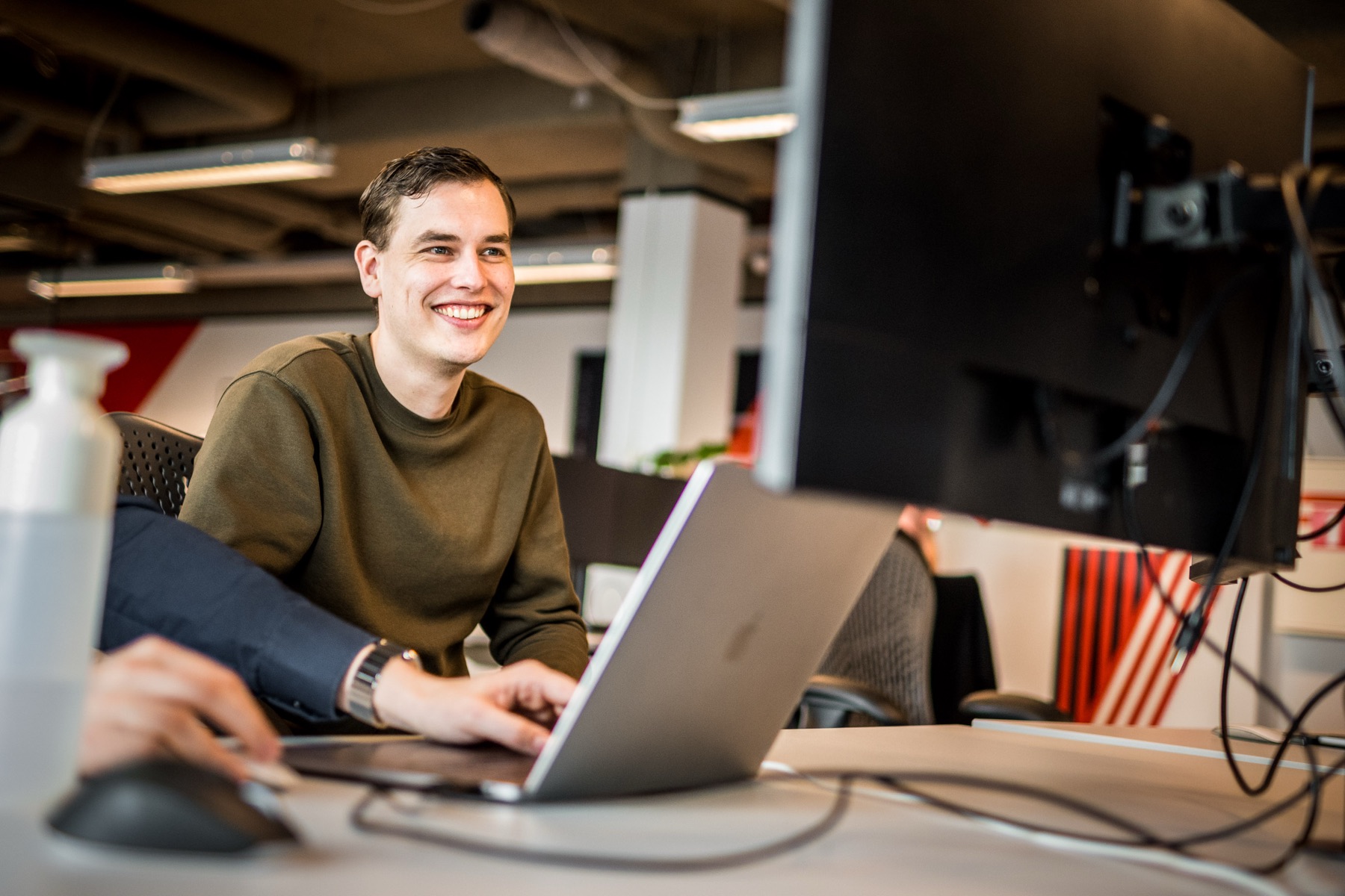 Collega lacht tijdens het werken achter zijn laptop