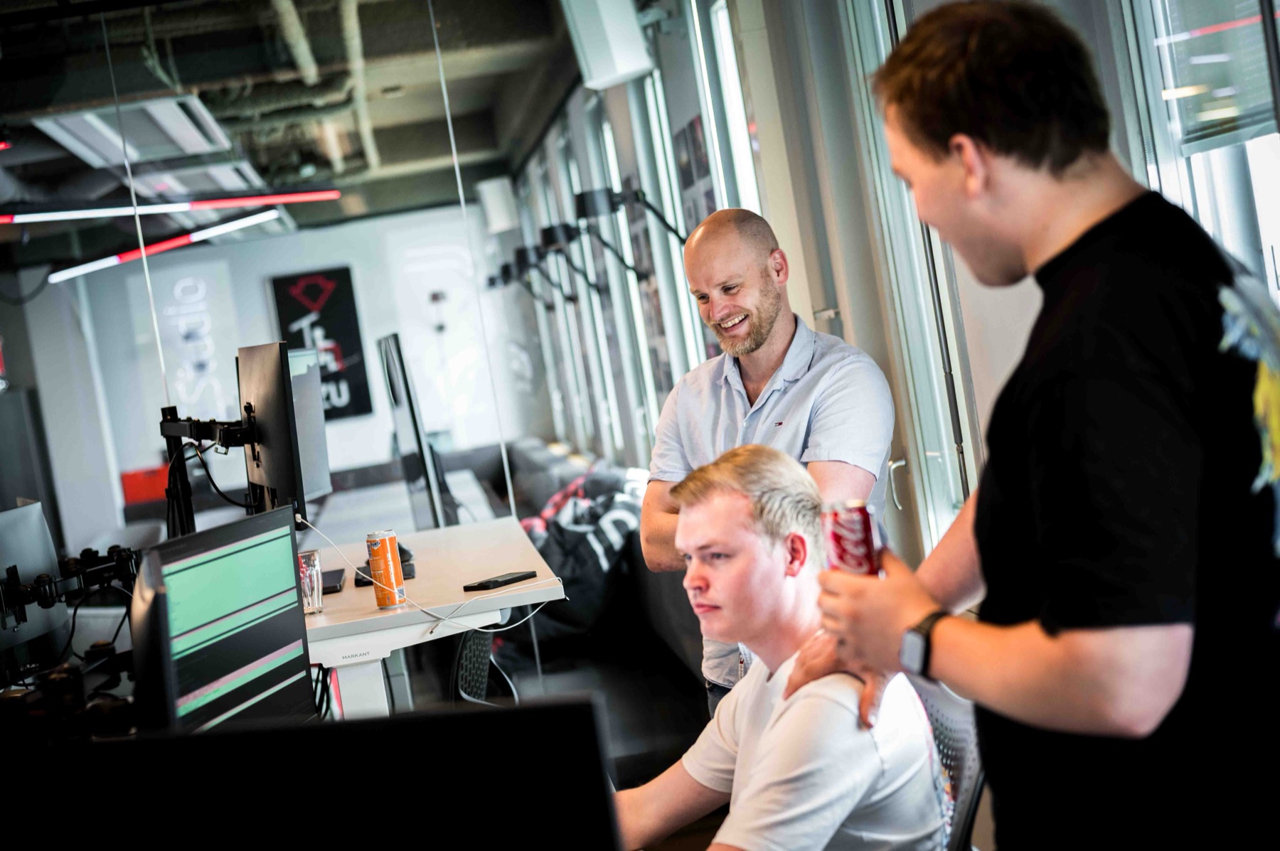 Drie collegas kijken samen naar een scherm