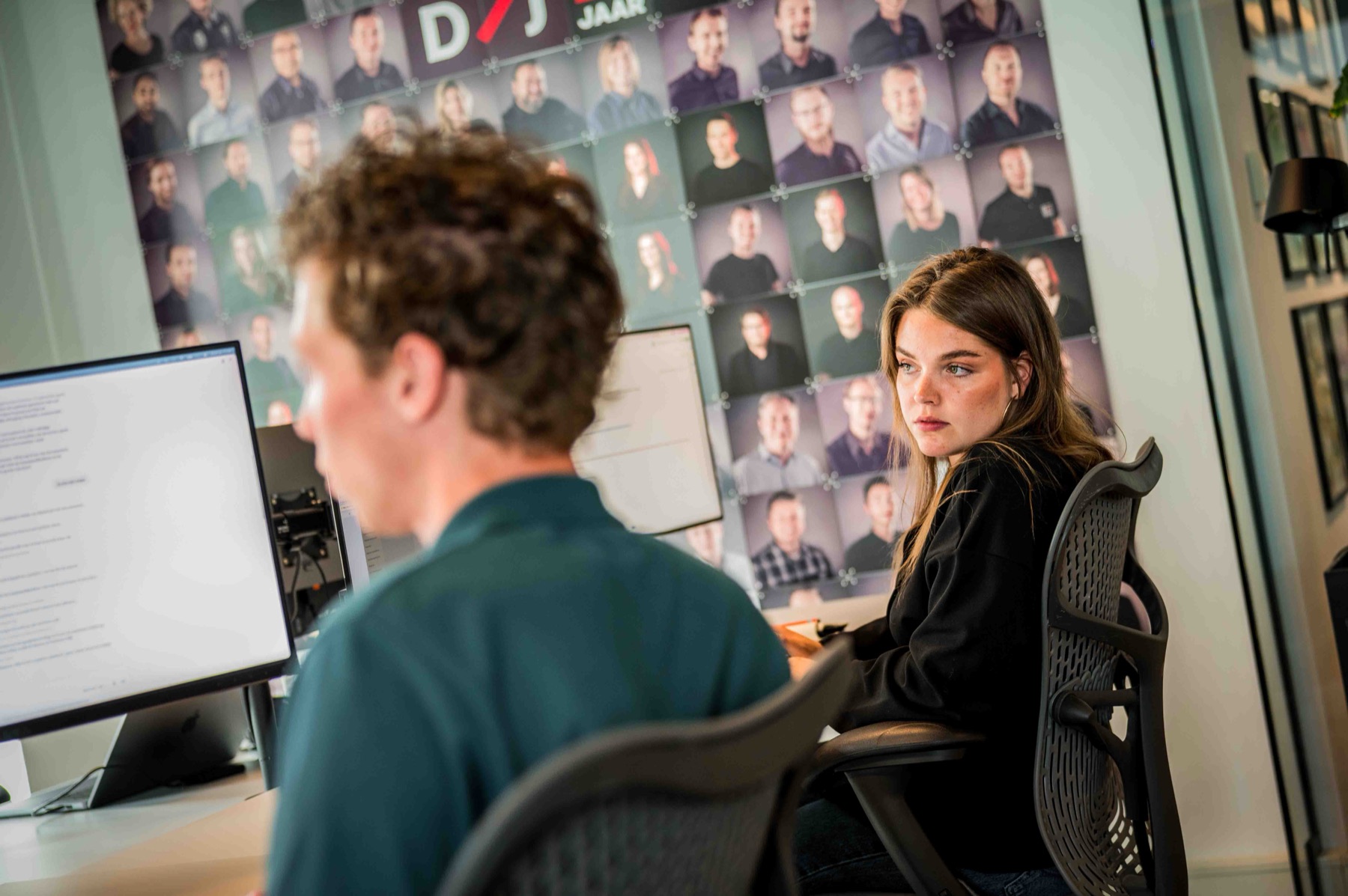 Twee collegas overleggen samen achter hun werkplek