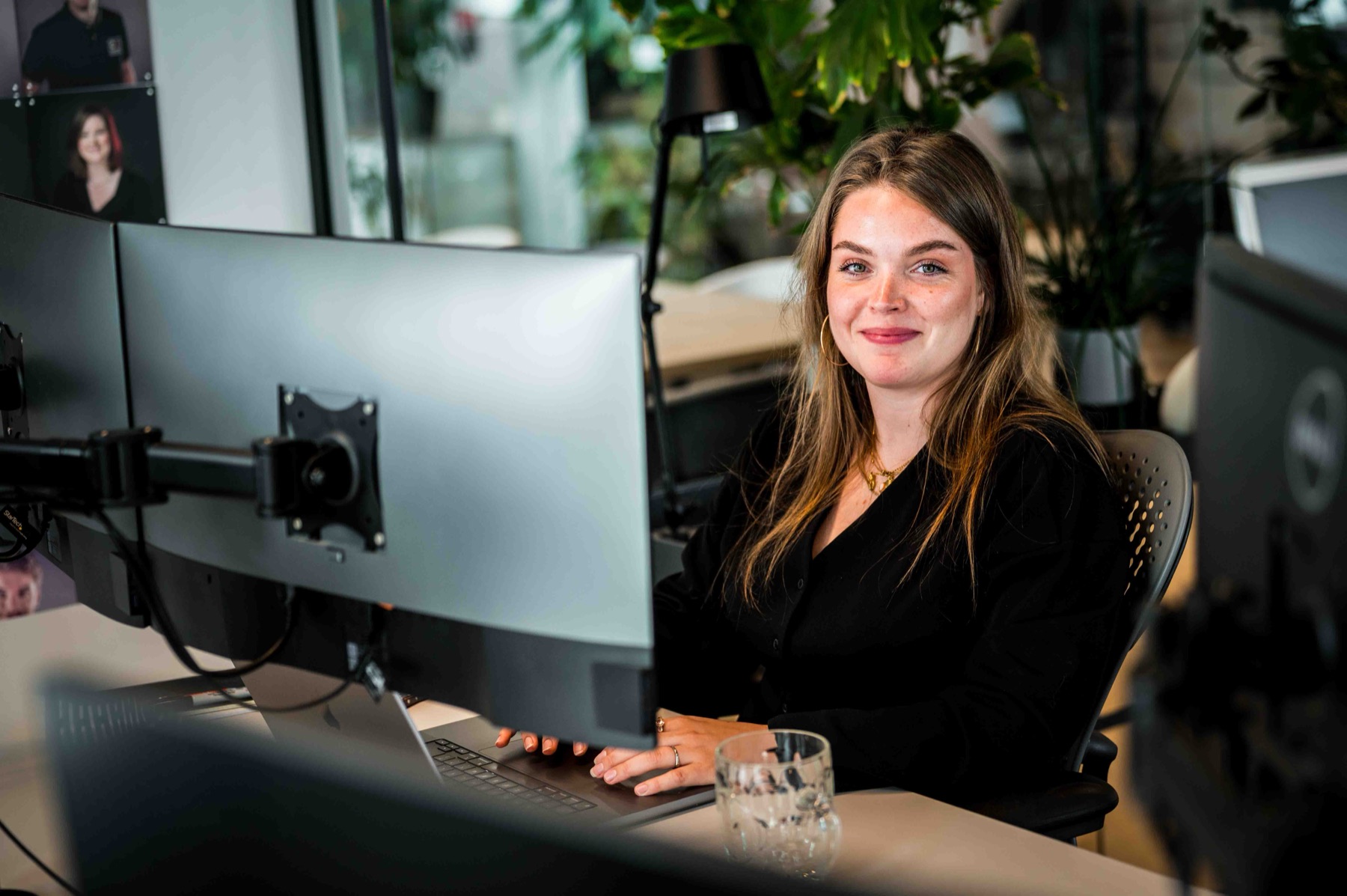 Collega lacht achter haar werkplek met twee schermen