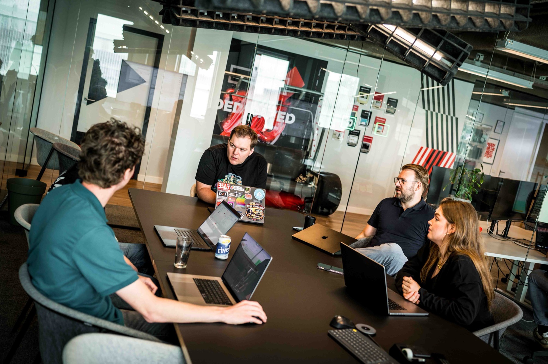 Teamoverleg met vier collegas rond de vergadertafel