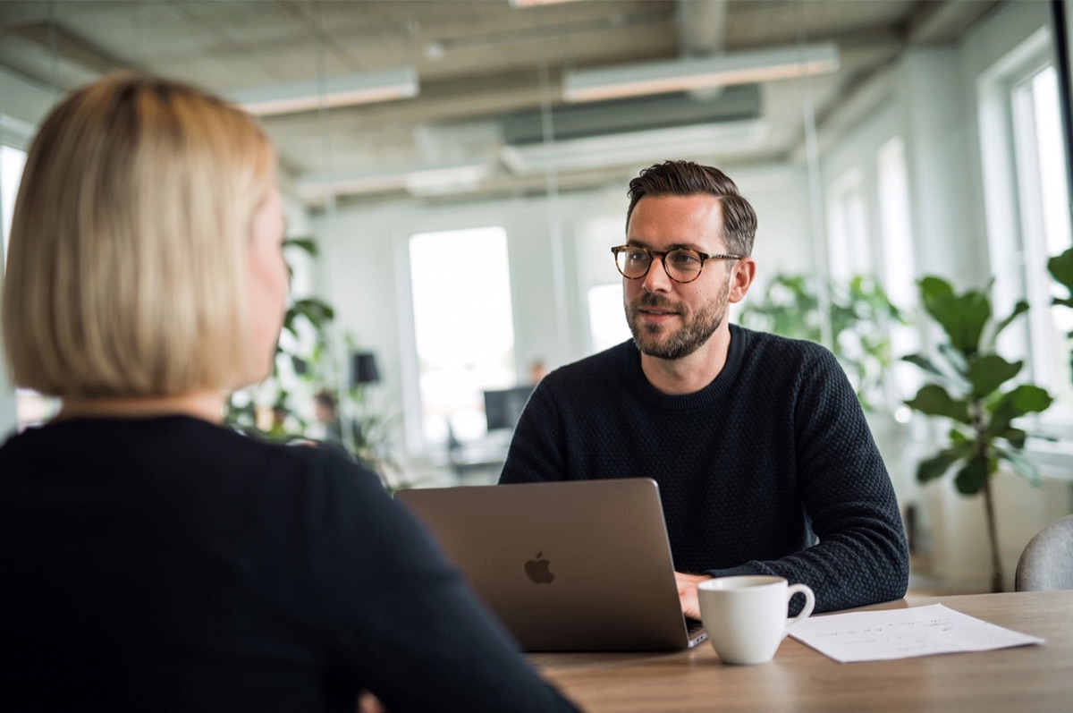 Adviseur in gesprek met een klant, met een laptop tussen hen in